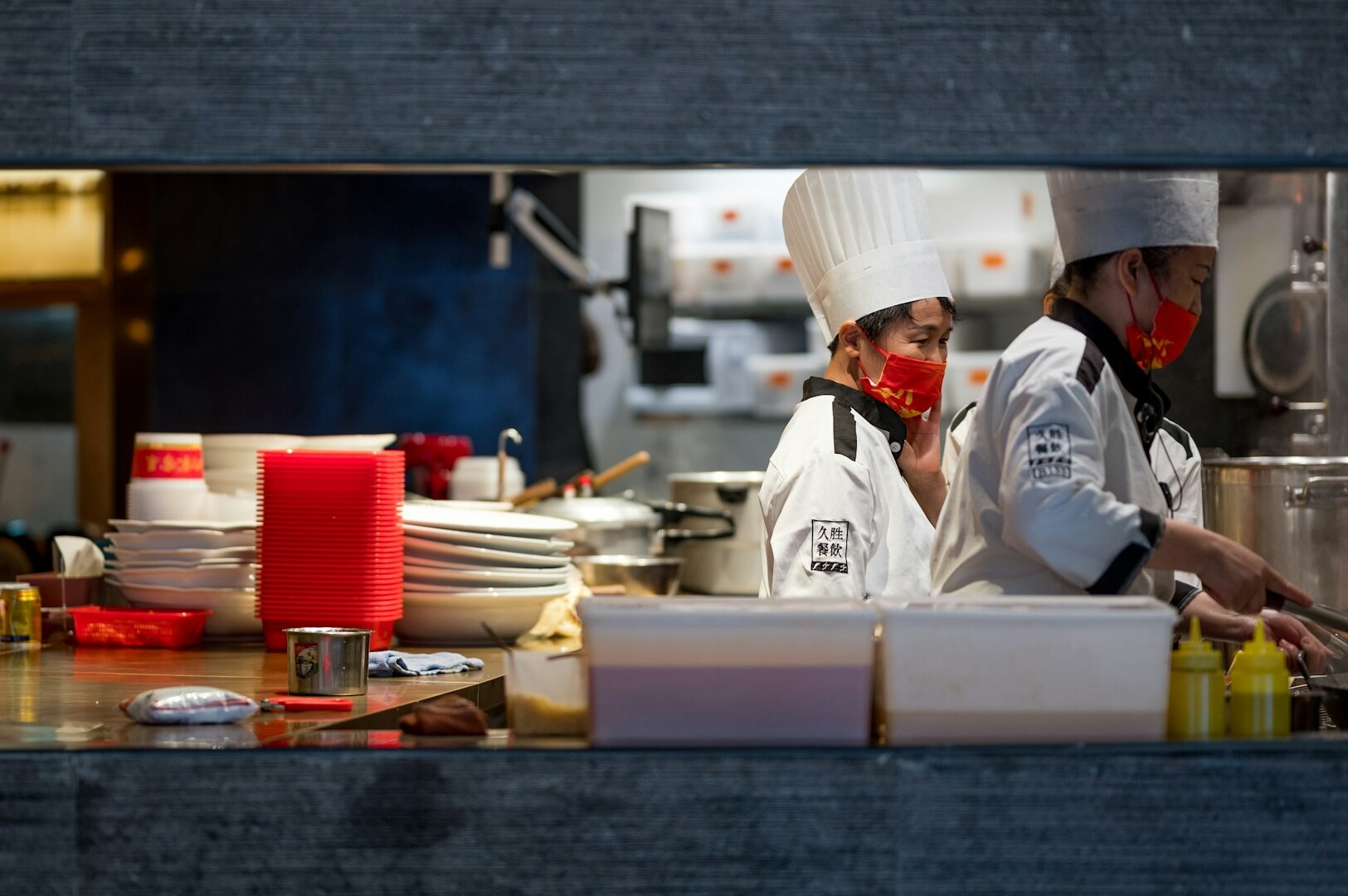 Inside a newly opened Michelin-starred restaurant, two chefs work together in a kitchen with a large window.