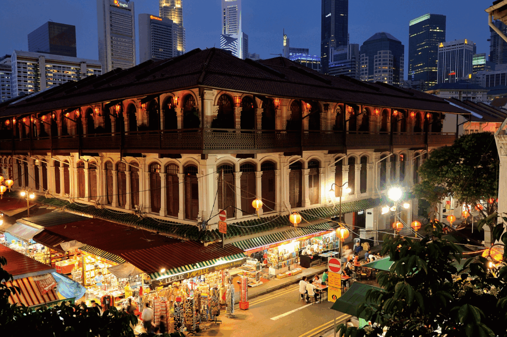 Evening view of Singapore’s Chinatown street market with colonial-style architecture, glowing lanterns, and bustling food stalls—capturing the vibrant nightlife and dining scene featured in “Singapore Chinatown Restaurants After Dark: A Night Owl’s Dining Guide.
