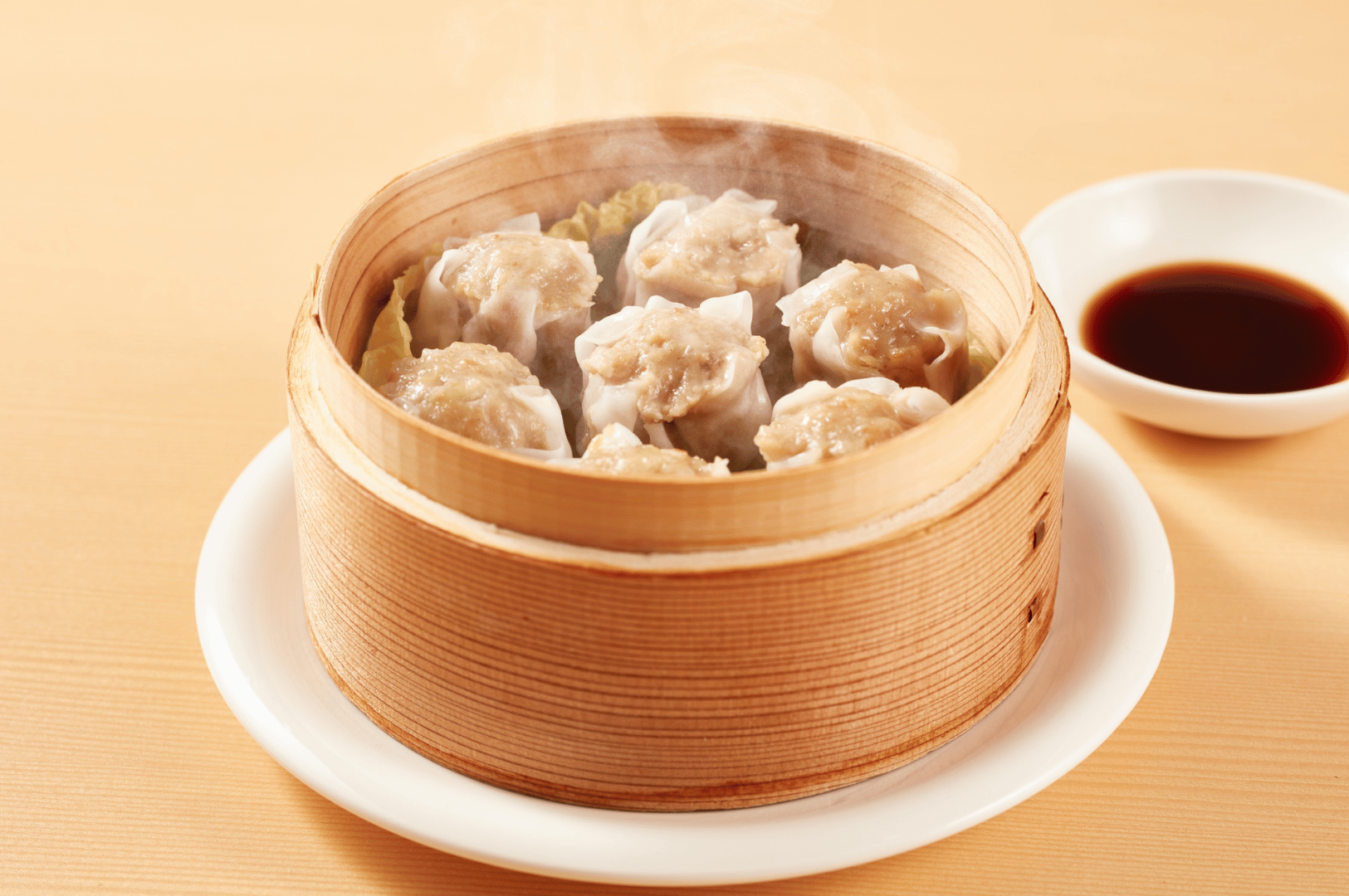 Freshly steamed shumai dumplings in a bamboo basket with dipping sauce—highlighting the authentic dim sum flavors night owls can savor in Singapore Chinatown’s late-night restaurant scene.
