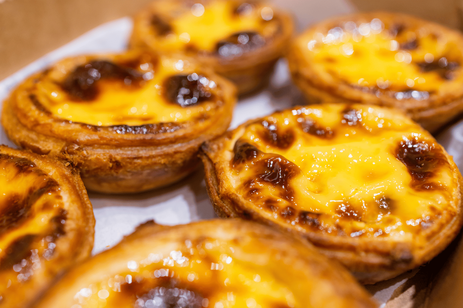 Close-up of freshly baked Portuguese egg tarts with caramelized custard and flaky crust—offering a sweet, late-night treat for diners exploring Singapore Chinatown’s after-dark food scene.