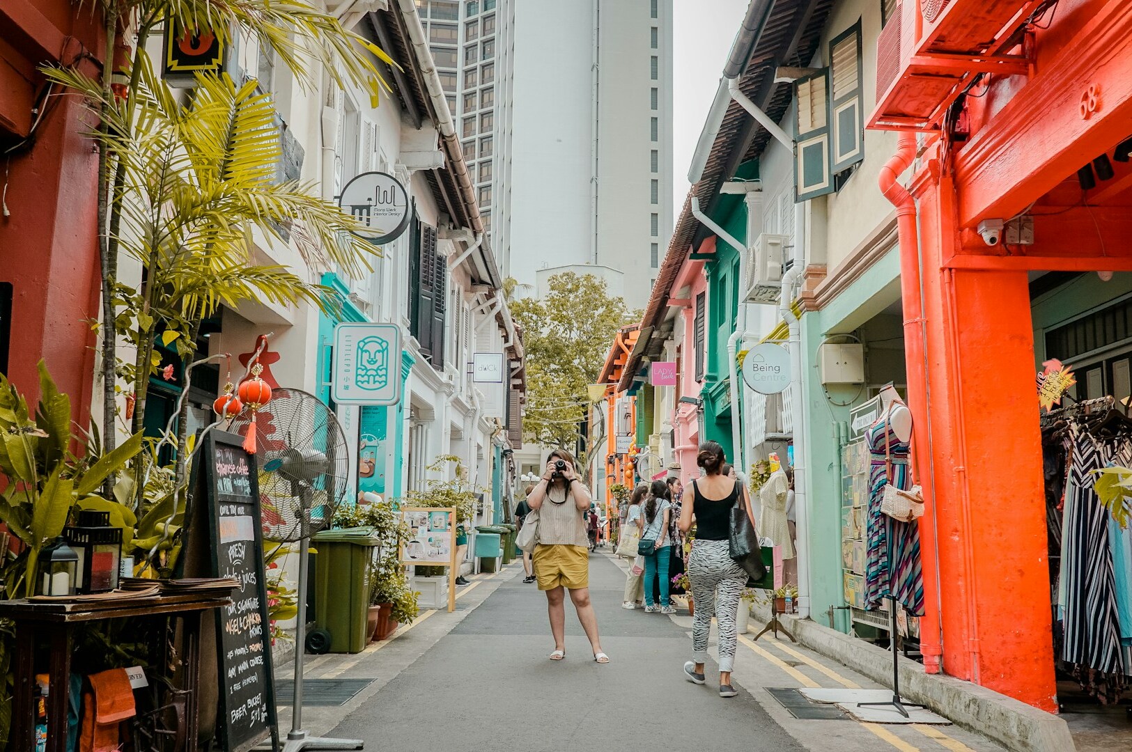 A woman strolls through a vibrant alleyway lined with colorful buildings in Kampong Glam, showcasing modern interpretations.