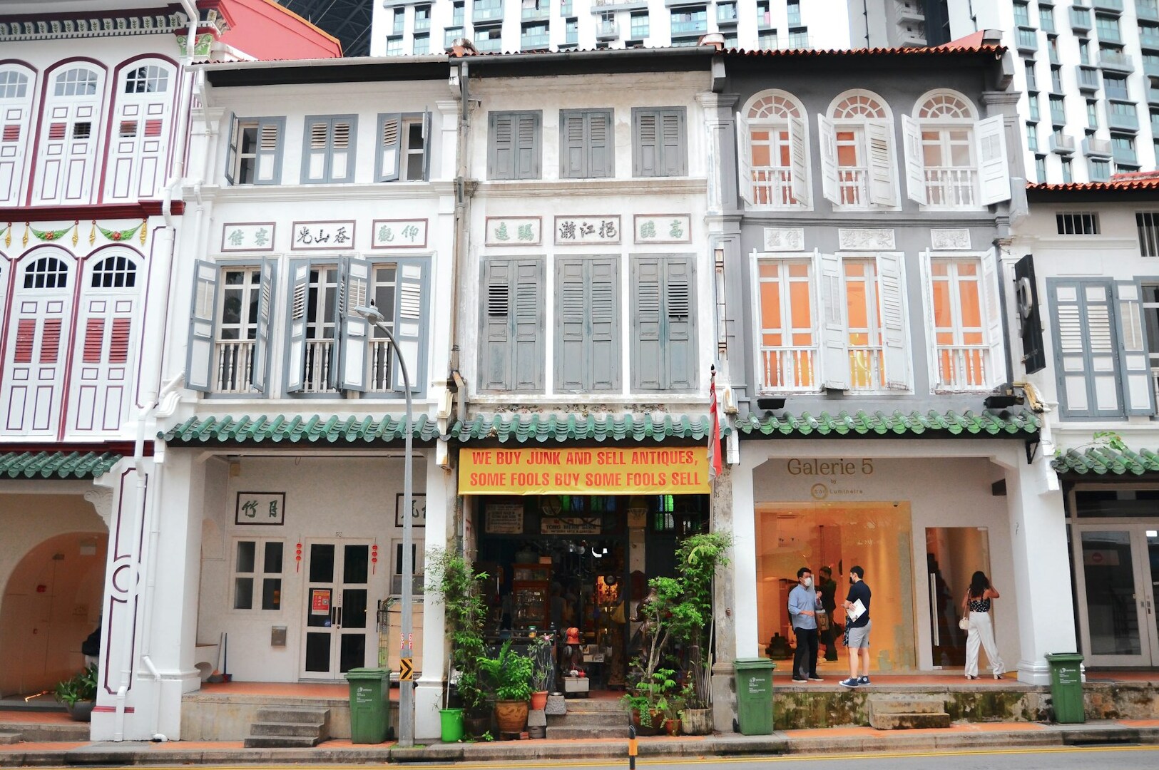 A row of modern buildings with pedestrians walking by, highlighting the vibrant atmosphere near the Peranakan restaurant.