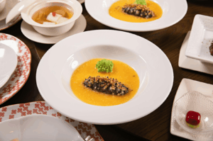 Elegant Michelin-starred tasting menu featuring artfully plated gourmet dishes, vibrant sauces, and refined textures at a Singapore fine dining restaurant.