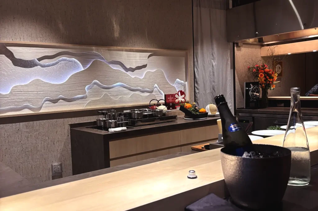 A close-up view of how a chef's table in Singapore unfolds course by course, highlighting a wooden counter setup, ambient lighting, and wine service.