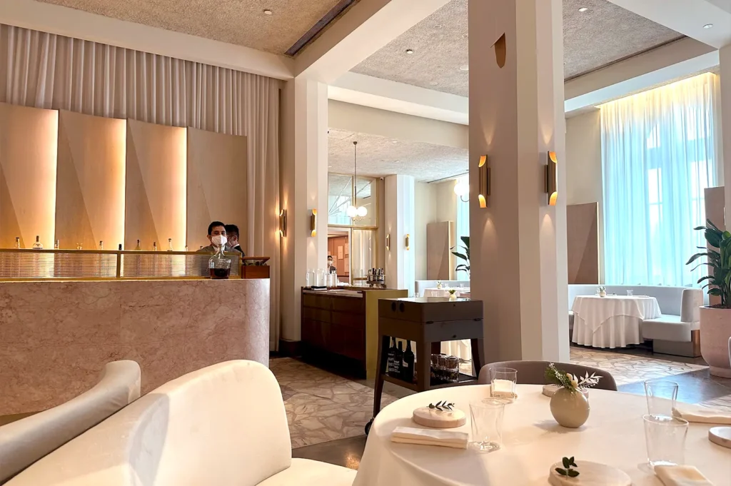 The sophisticated interior of Odette in Singapore, showcasing high ceilings, soft white drapery, and fine dining tables set for an intimate meal.