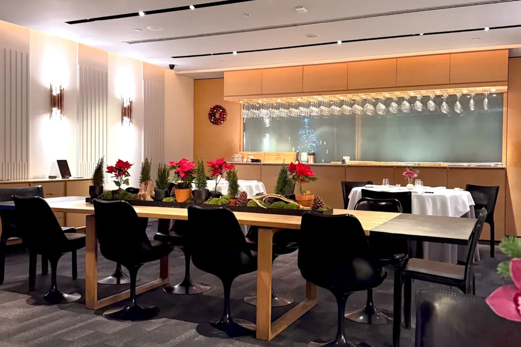 Iggy's dining room in Singapore featuring a refined layout with floral centerpieces, comfortable black chairs, and a sleek bar area.