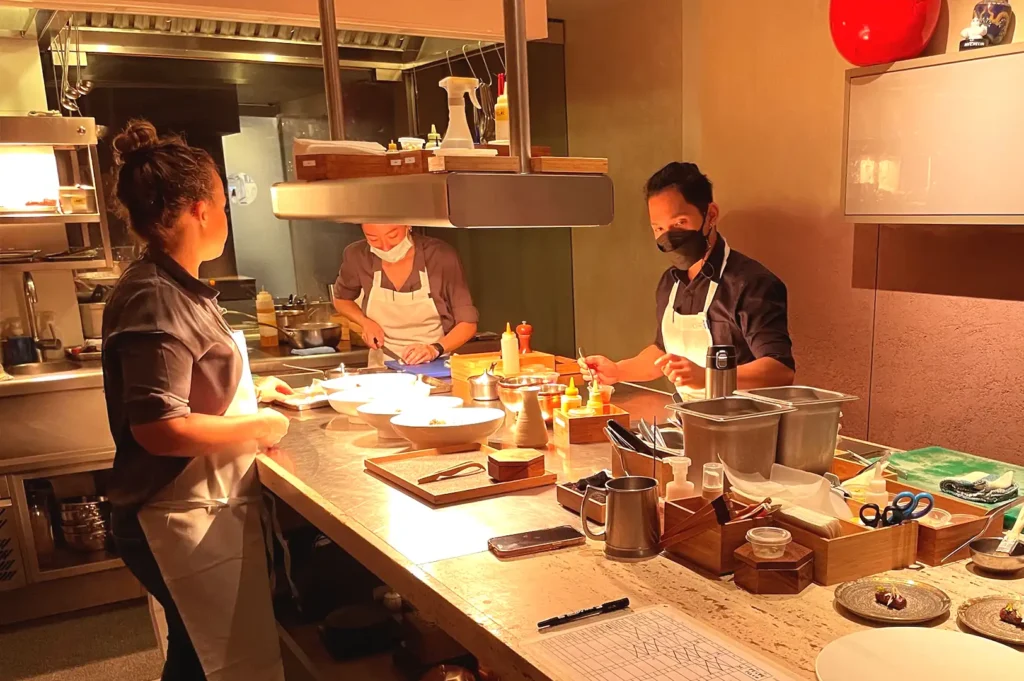 Chefs working meticulously in the open kitchen at Nouri, demonstrating how the chef's table concept opened up interactive fine dining in Singapore.