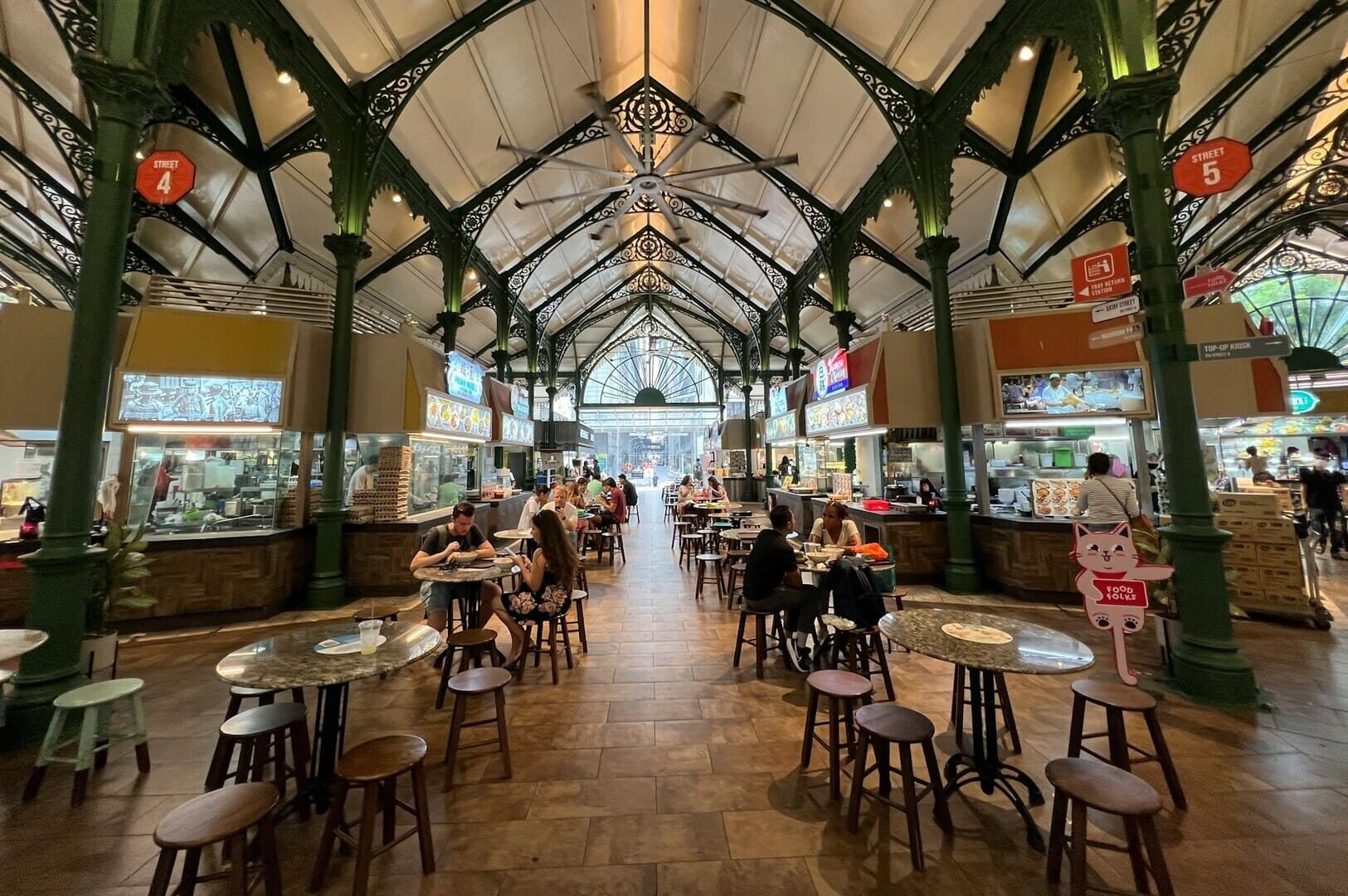 A bustling food court in Singapore, featuring various hawker stalls offering diverse local dishes and vibrant seating areas.