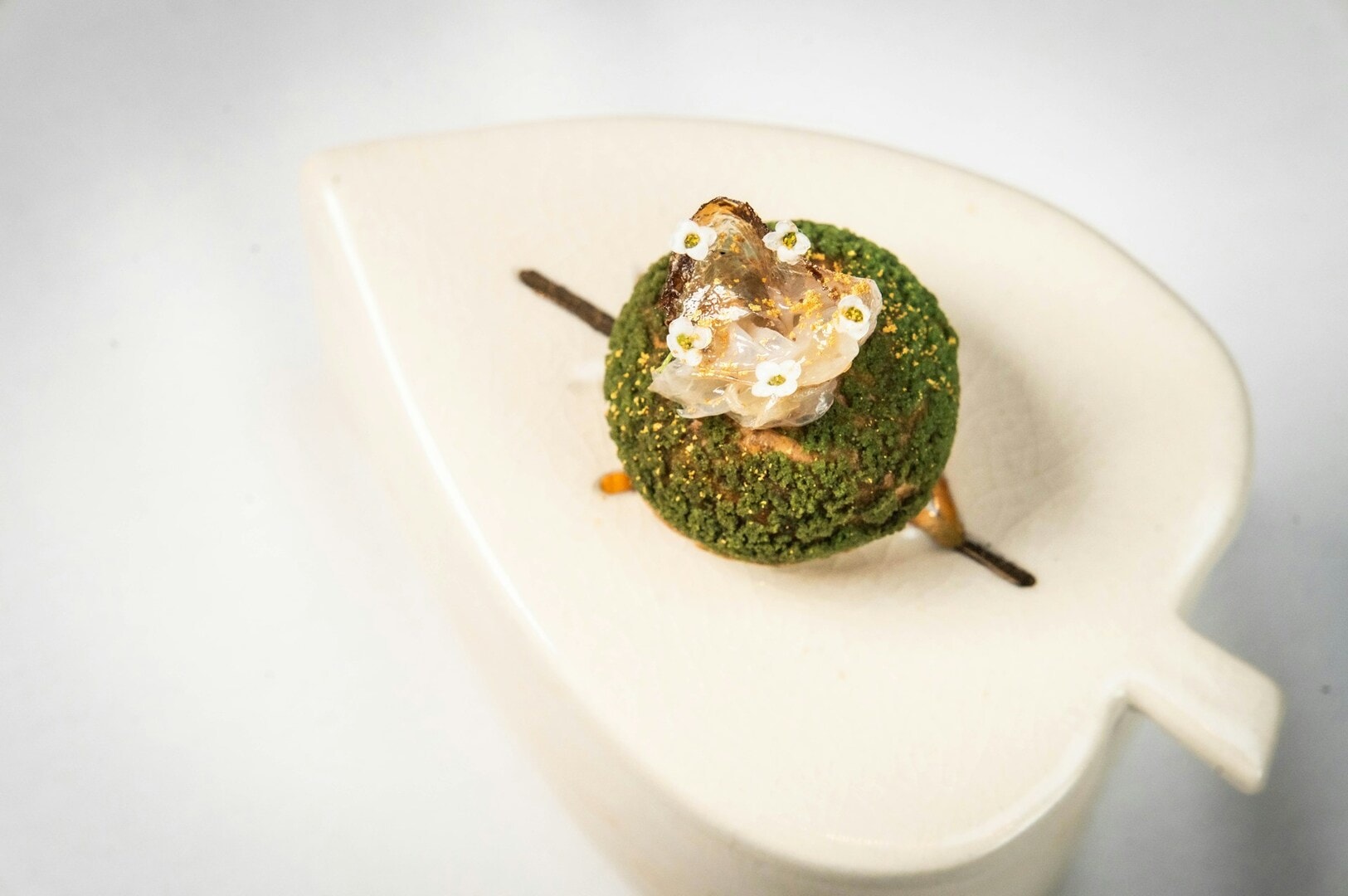 A matcha-flavored cupcake elegantly placed on a white plate, showcasing a piece of gastronomic art.