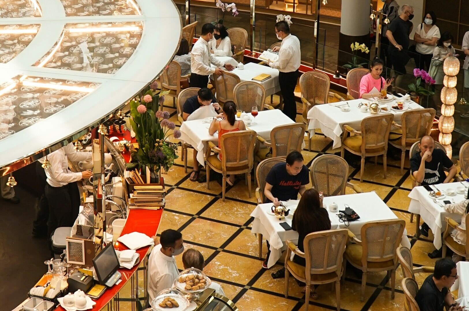 A bustling dining room in a Singapore restaurant, filled with people enjoying meals and drinks together.