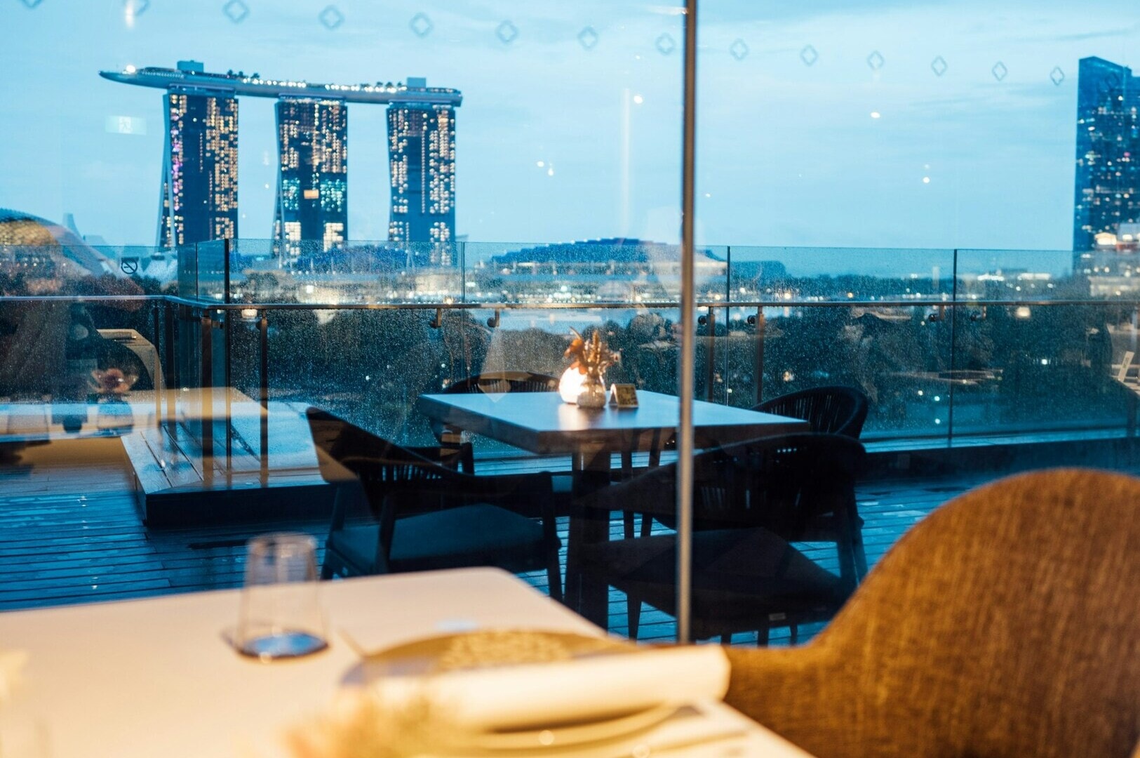 A night view of a Singapore restaurant overlooking the illuminated city skyline.