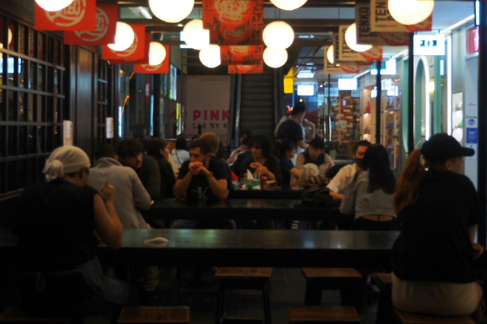 Diners seated at tables in a bustling restaurant in Singapore, engaged in lively discussions over their meals.