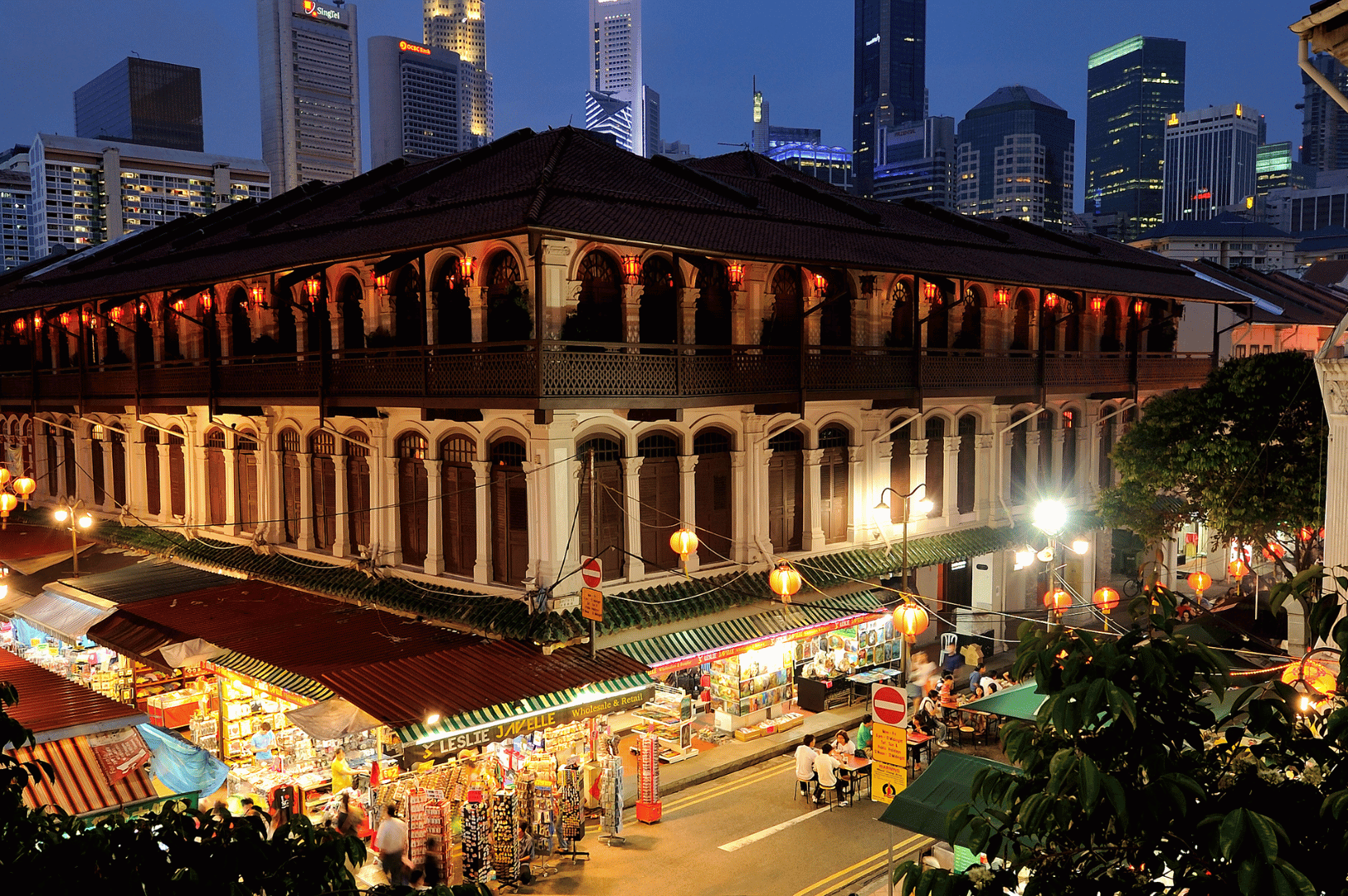 Evening view of Singapore’s Chinatown street market with colonial-style architecture, glowing lanterns, and bustling food stalls—capturing the vibrant nightlife and dining scene featured in “Singapore Chinatown Restaurants After Dark: A Night Owl’s Dining Guide.