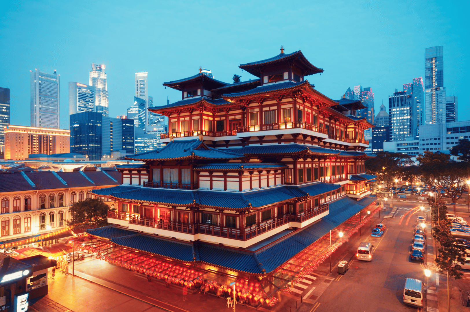 Night view of Singapore’s Buddha Tooth Relic Temple glowing with lanterns and Tang-style architecture—anchoring the cultural heart of Chinatown’s vibrant after-dark dining and street life.