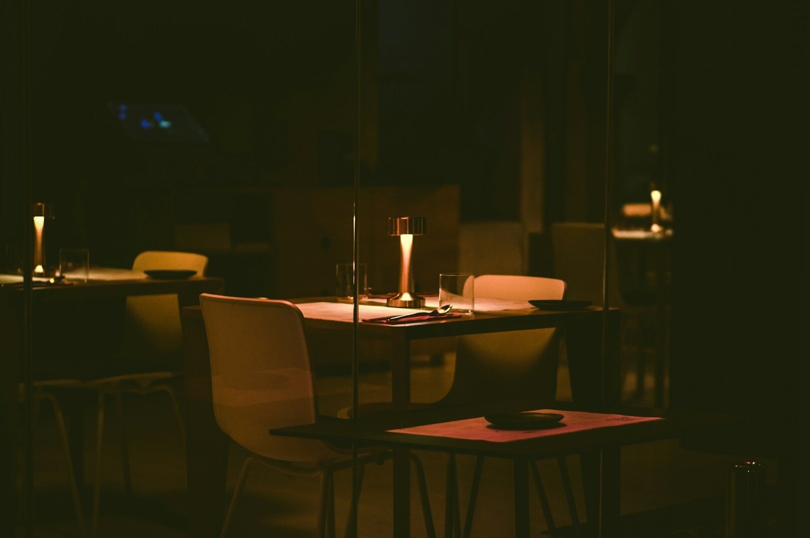 A cozy table set in darkness, illuminated by a glowing candle, perfect for a romantic evening.