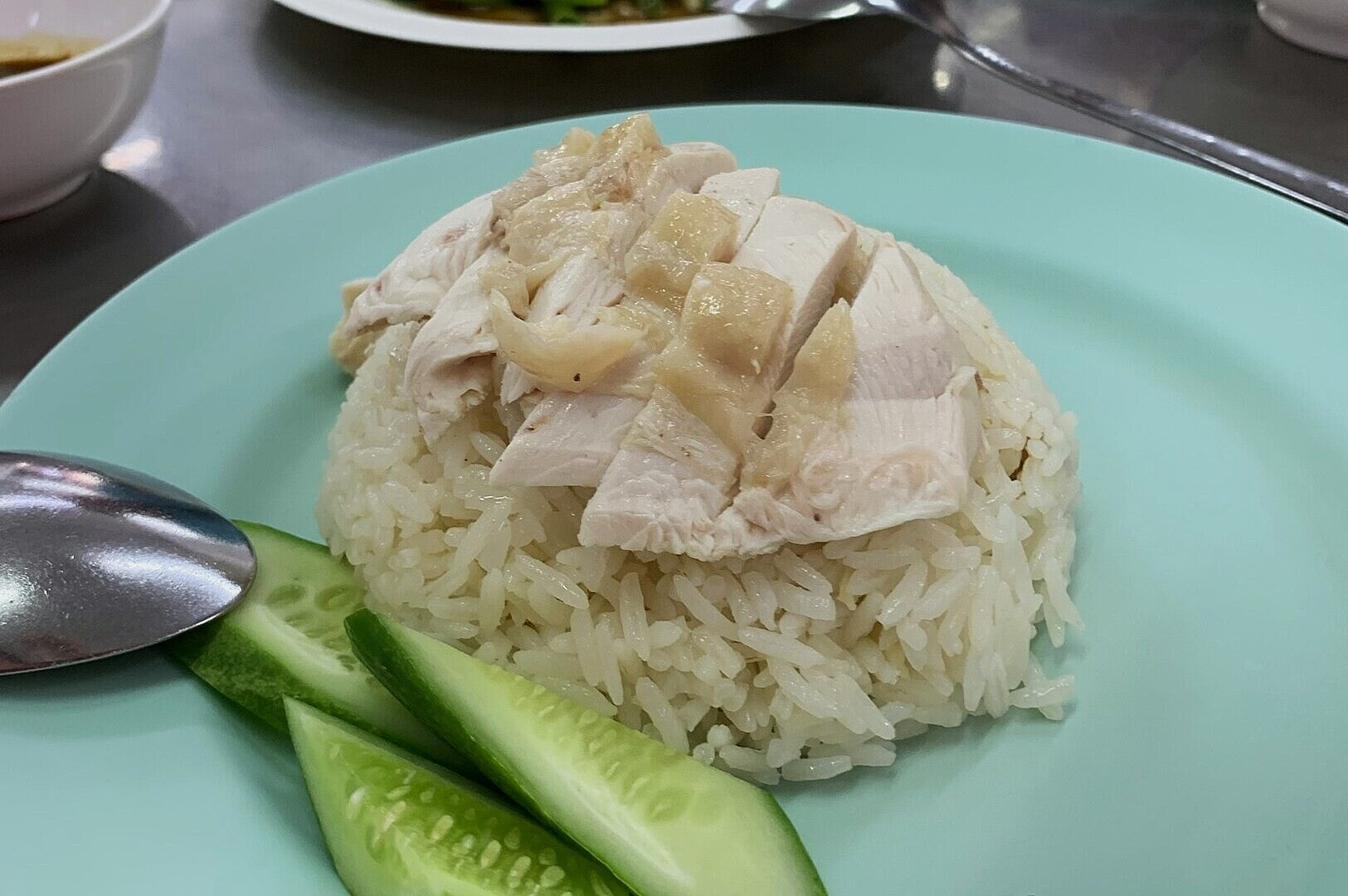 A plate of chicken rice featuring tender chicken pieces served over a bed of fluffy white rice.
