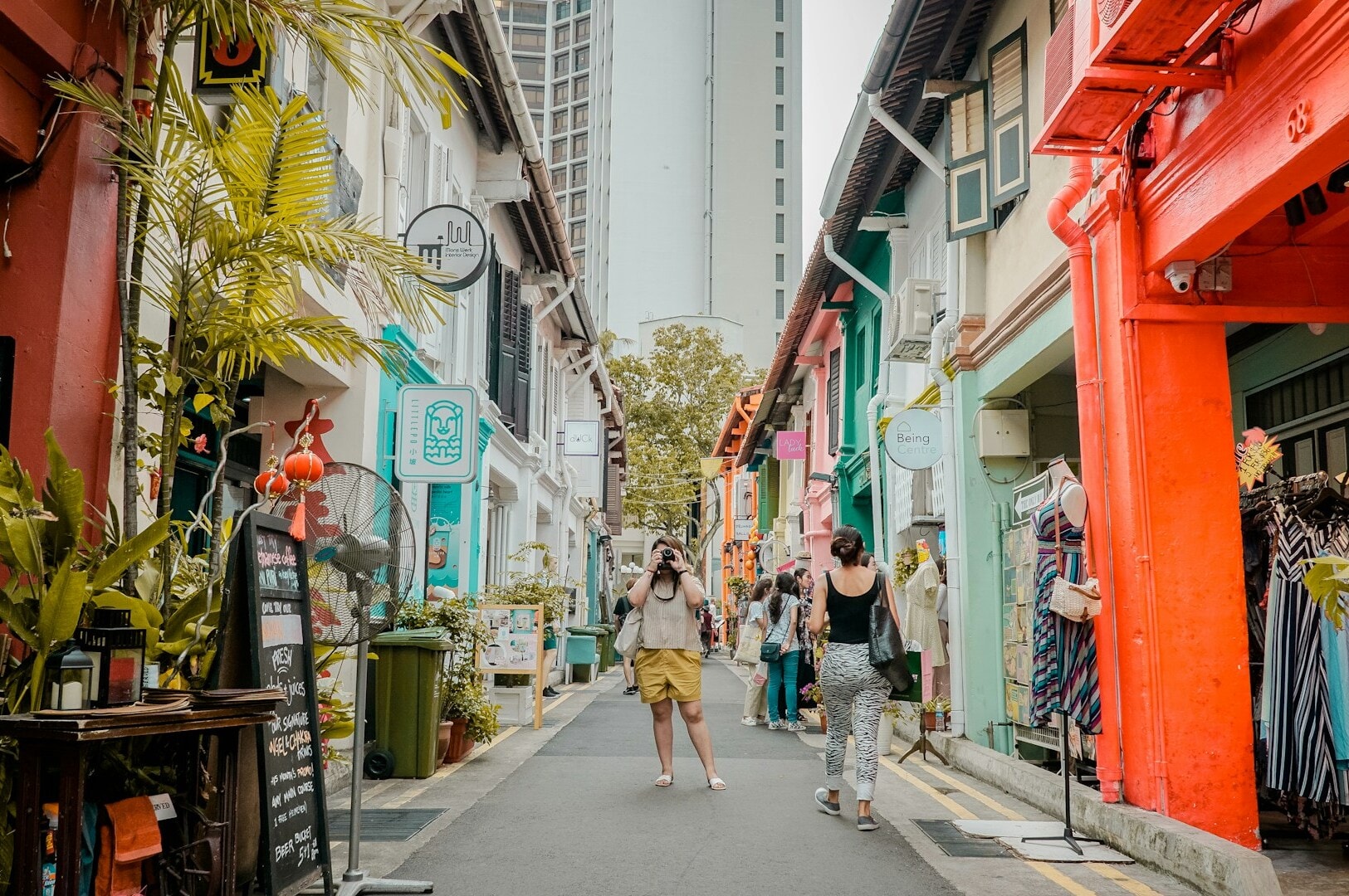A woman strolls through a vibrant alleyway lined with colorful buildings in Kampong Glam, showcasing modern interpretations.
