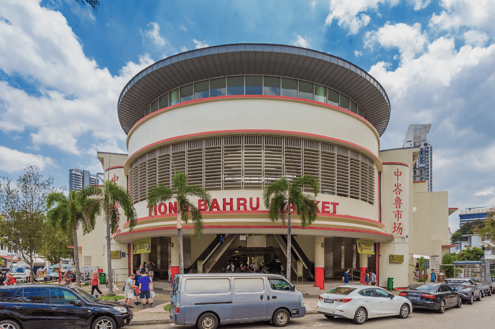 A vibrant scene of Tiong Bahru Market, featuring a curved facade with red accents, palm trees, and several parked cars. People walk around under a sunny sky.