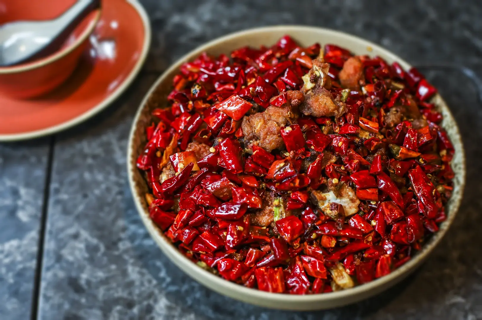 Chongqing chicken with Sichuan peppercorns and dried red chili peppers in a traditional Chinese bowl.