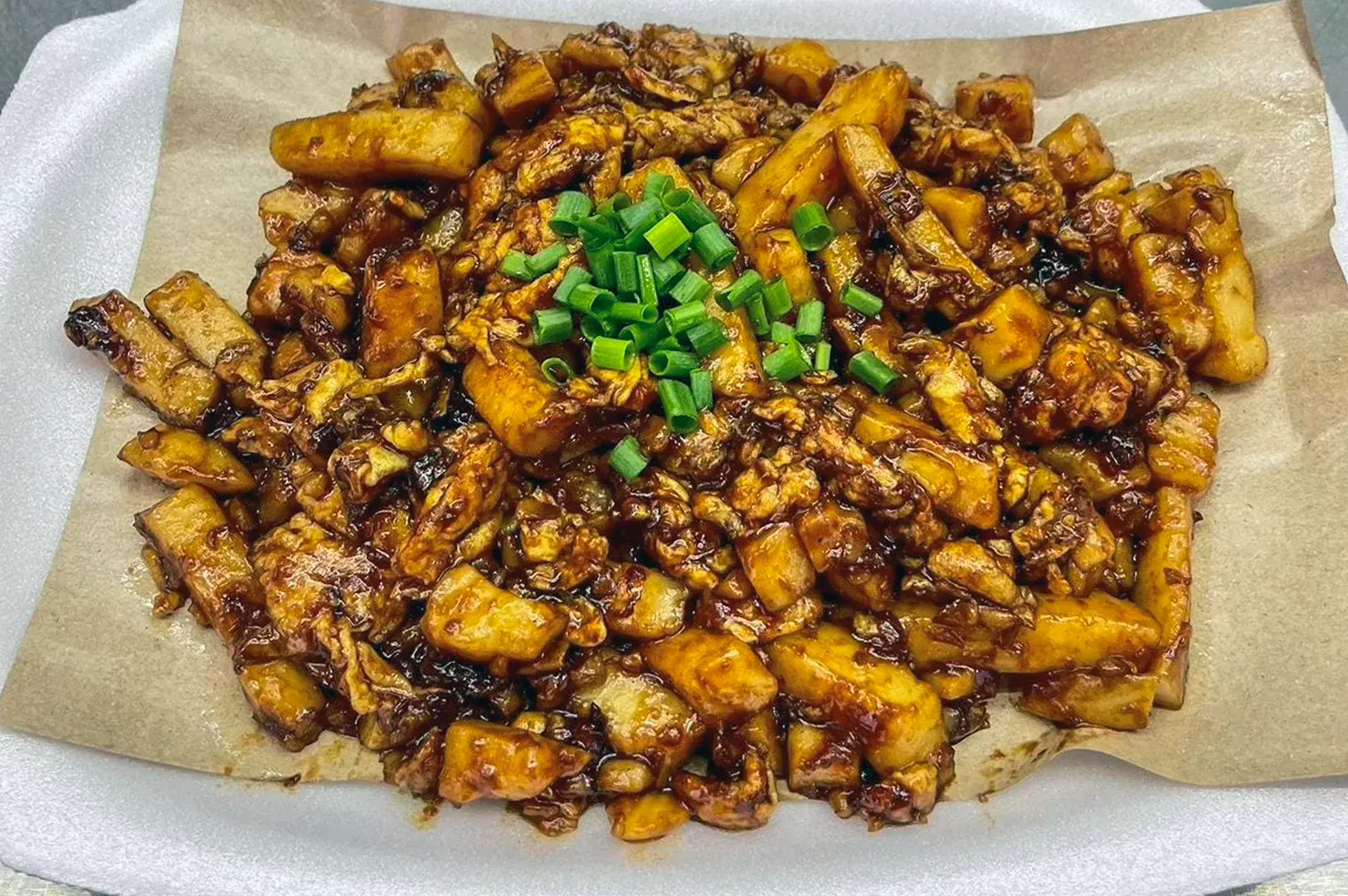 Singapore-style black carrot cake with stir-fried radish cubes coated in dark soy sauce and topped with chopped green onions.
