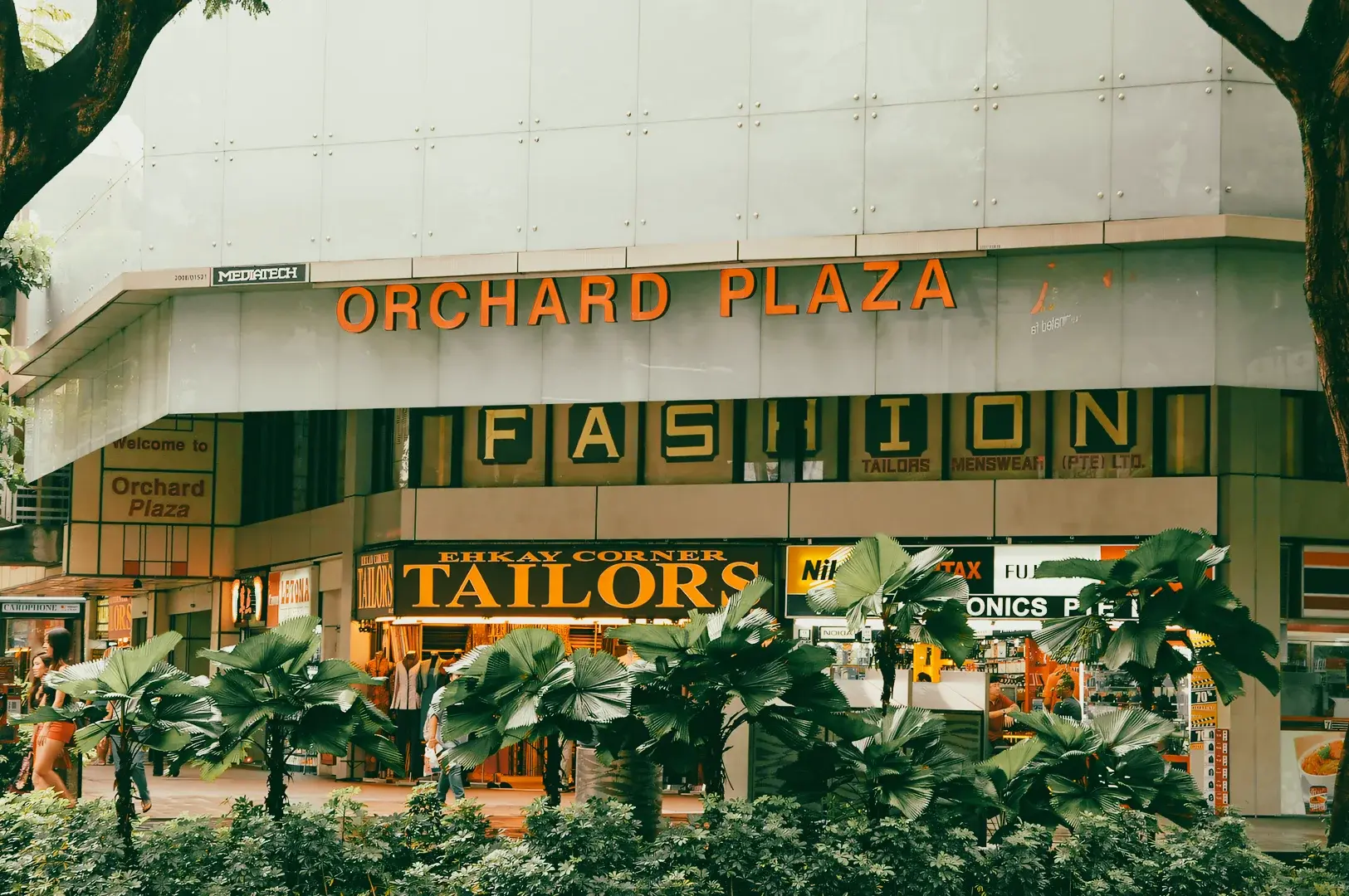 Wide-angle street-level shot of Orchard Plaza on Orchard Road Singapore, featuring storefronts and signage of the dining and shopping complex
