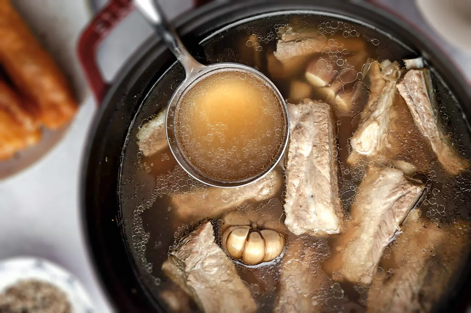 Traditional Singapore Bak Kut Teh pork rib soup simmered in a peppery garlic broth, served hot in a clay pot as a classic local comfort dish.