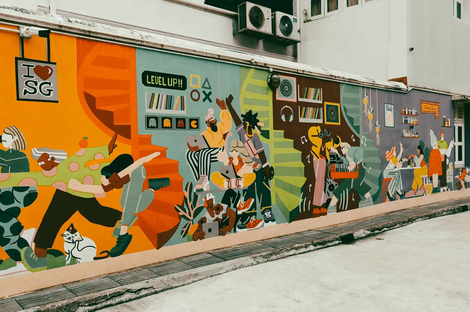 Eye‑level wide‑angle shot of Bugis Street Art Lane in Singapore, featuring a long colorful mural painted across a building wall with illustrated figures, abstract shapes, books, music elements, and “I ♥ SG” street art details in an urban alley setting.