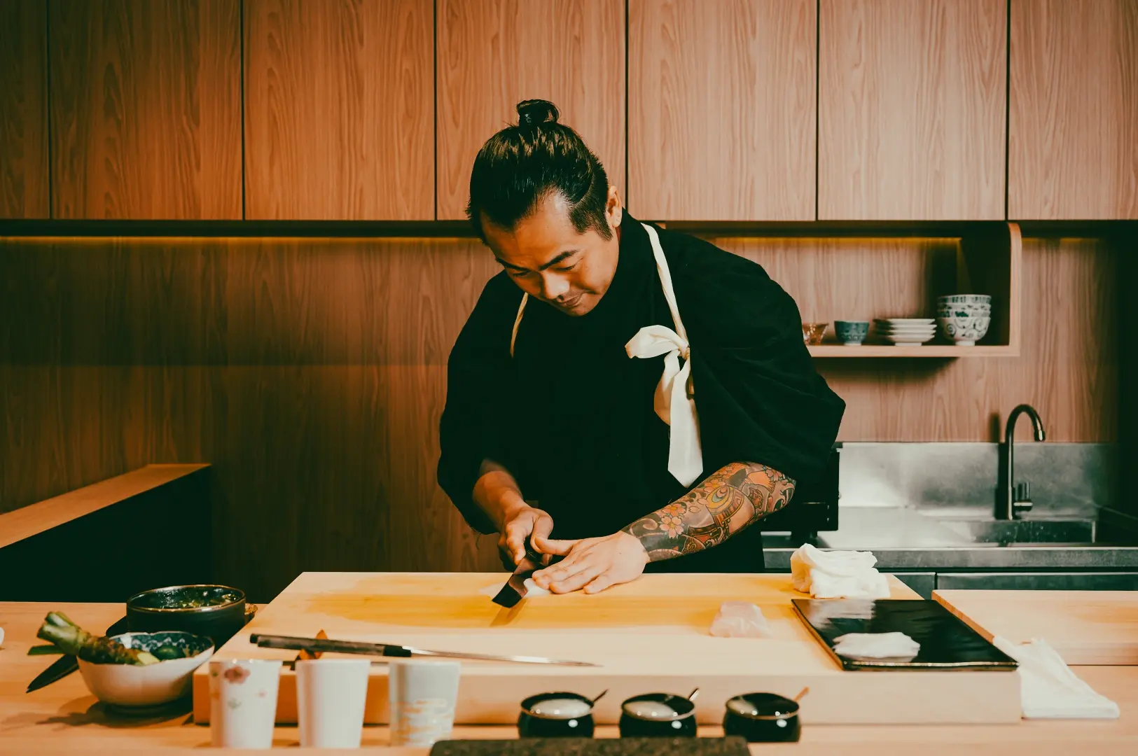 Chef preparing a dish at a modern Singapore restaurant, capturing experiential dining and contemporary culinary craftsmanship.