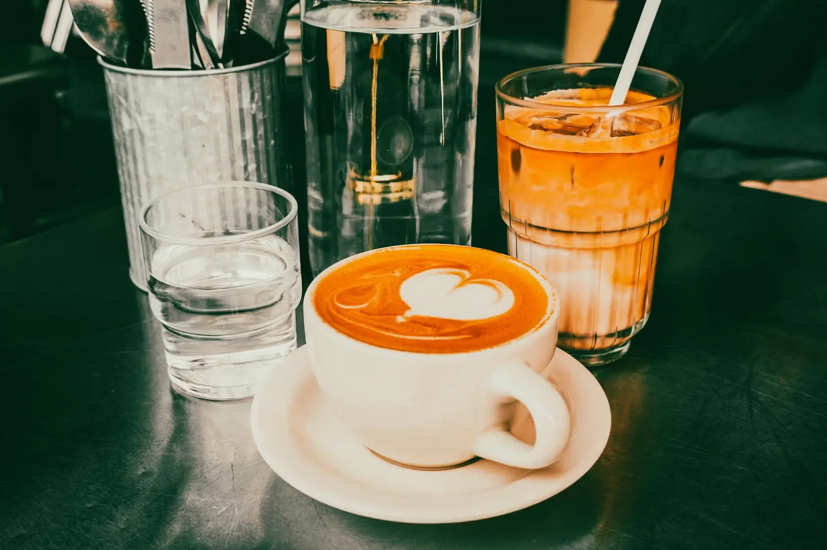 Close-up shot of latte art espresso coffee with iced latte and brewing tools on a cafe counter, highlighting barista craftsmanship in Singapore specialty coffee scene