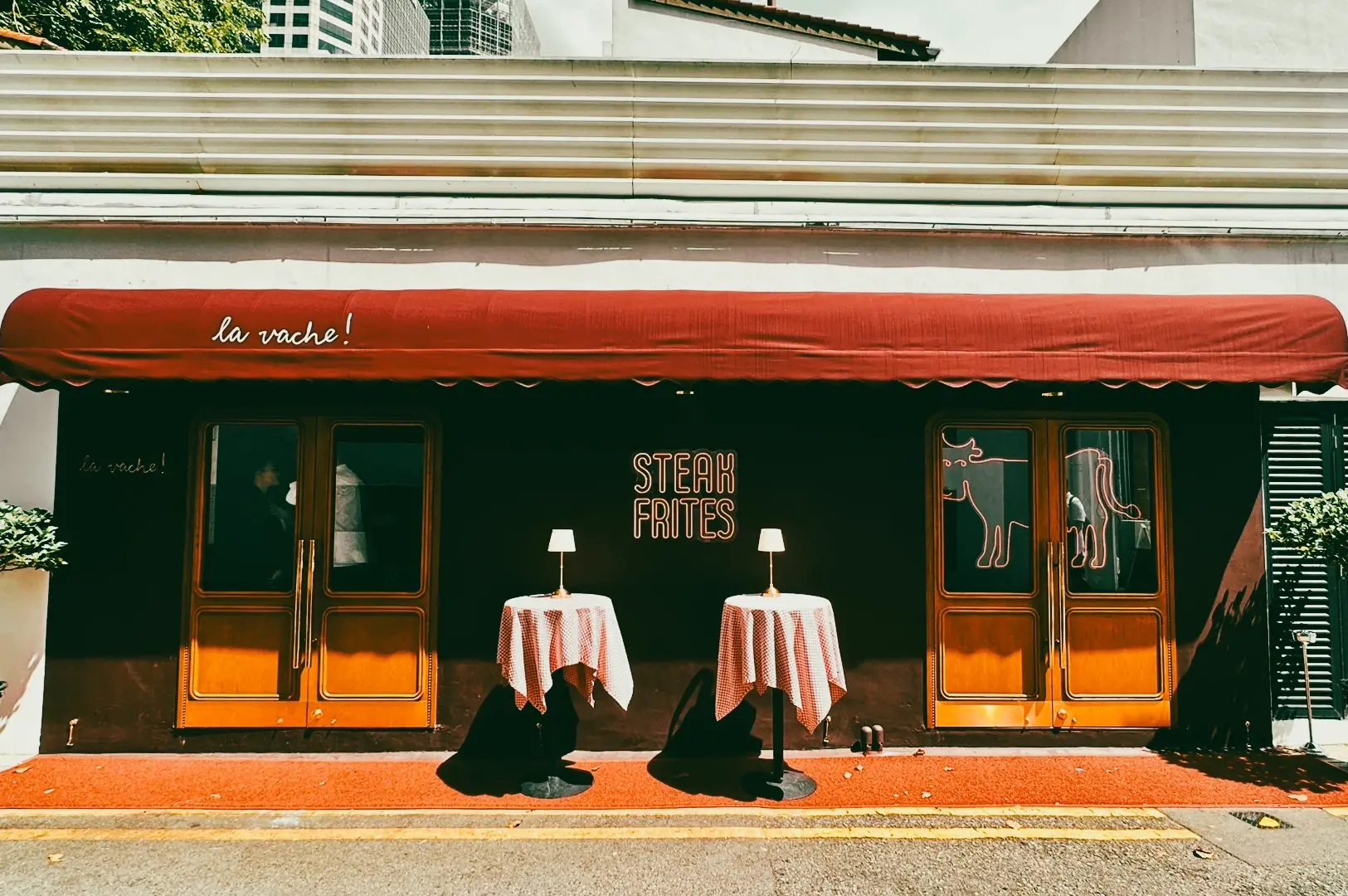 Exterior of a Singapore restaurant with red awning and outdoor tables, photographed straight-on from street-level perspective highlighting steak frites signage.
