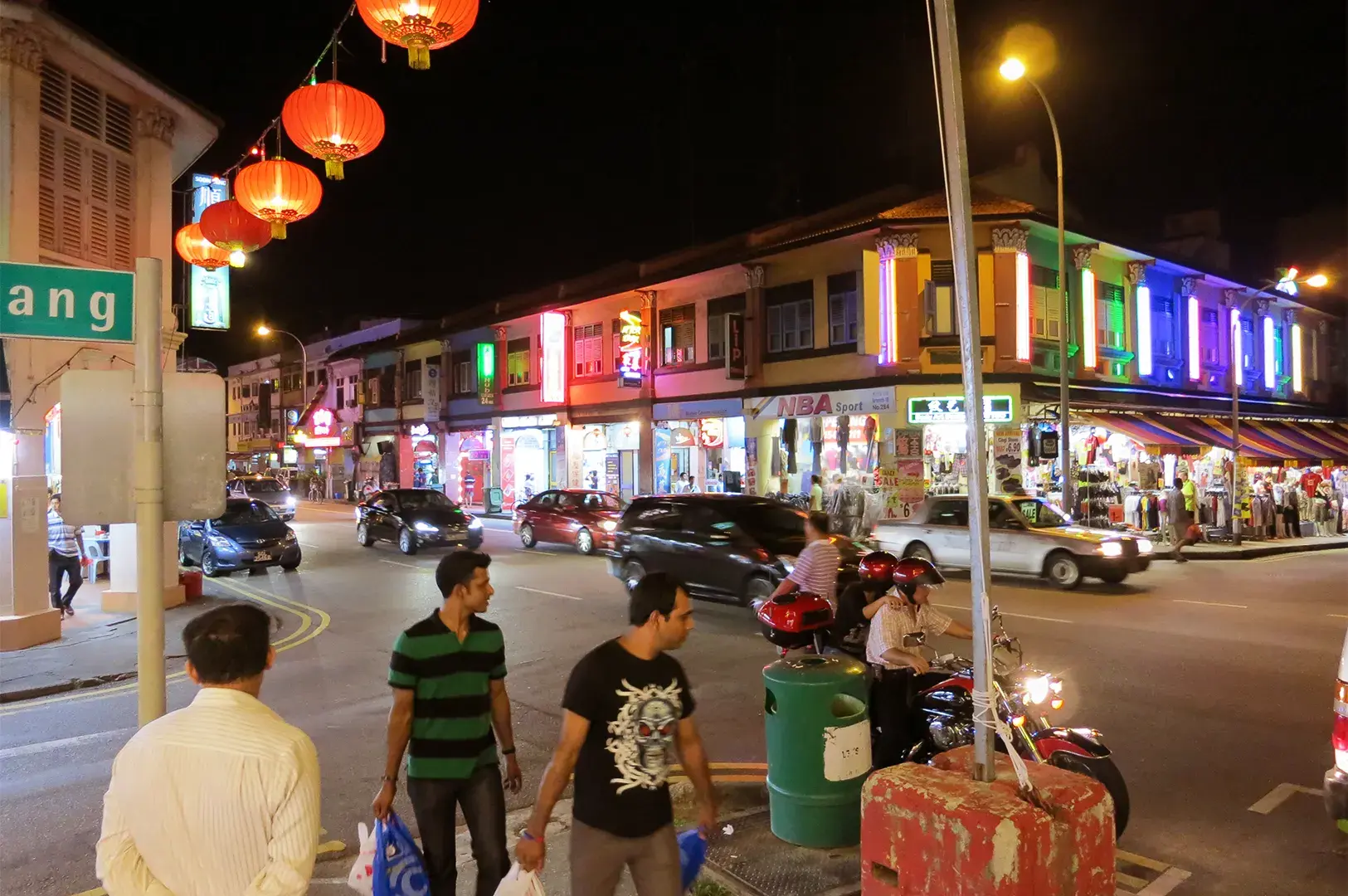 A bustling night street scene in Geylang, Singapore, featuring iconic red lanterns lining the roads, capturing the vibrant atmosphere of the district's famous late-night supper culture.