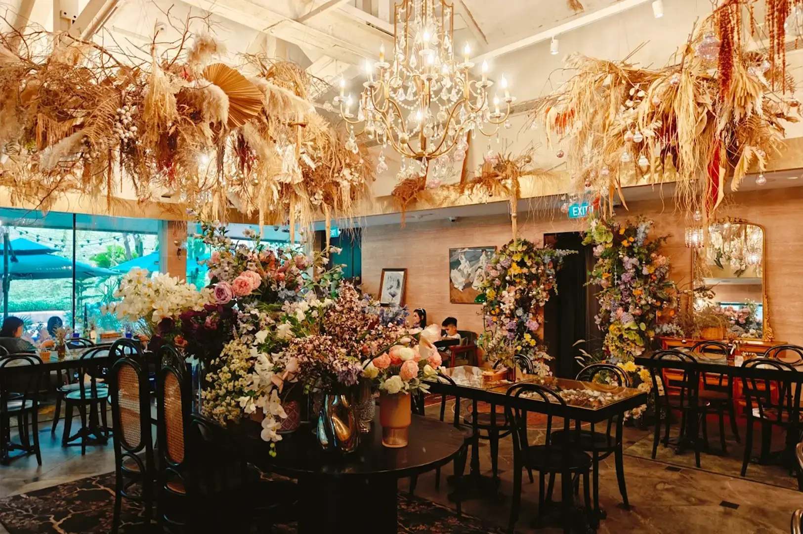 Elegant interior of Le Jardin restaurant in Singapore, showcasing a floral-themed dining room with dramatic dried flower installations, chandeliers, and vintage-style furniture.
