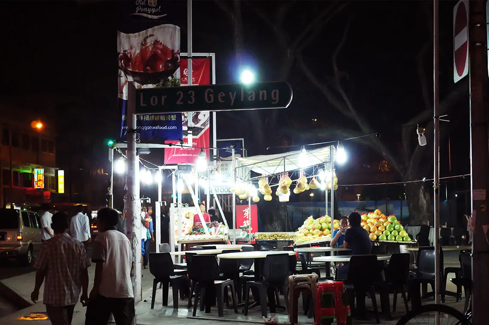 A nighttime street scene at Lorong 23 Geylang, capturing the vibrant atmosphere of local food spots, perfect for satisfying midnight cravings with its bustling outdoor seating and illuminated stalls.