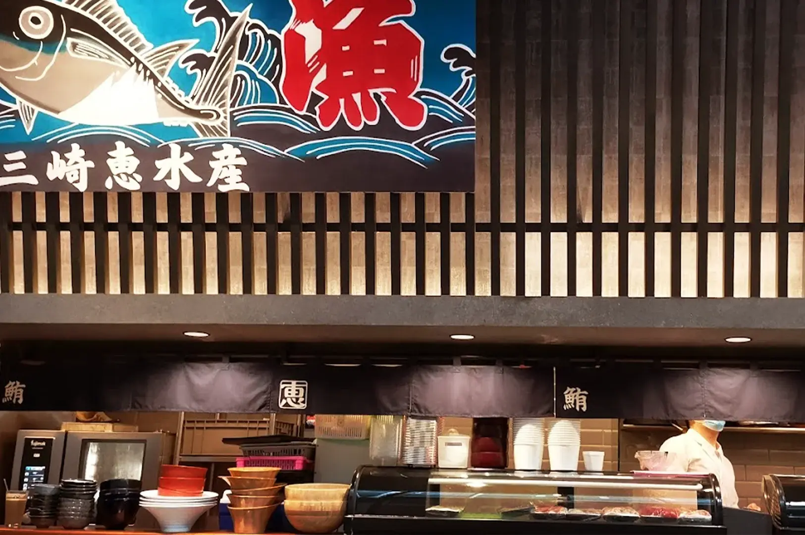 Close-up view of the interior kitchen area at Kuro Maguro Sushi and Dining, featuring traditional Japanese signage and a clean, authentic sushi bar setup.