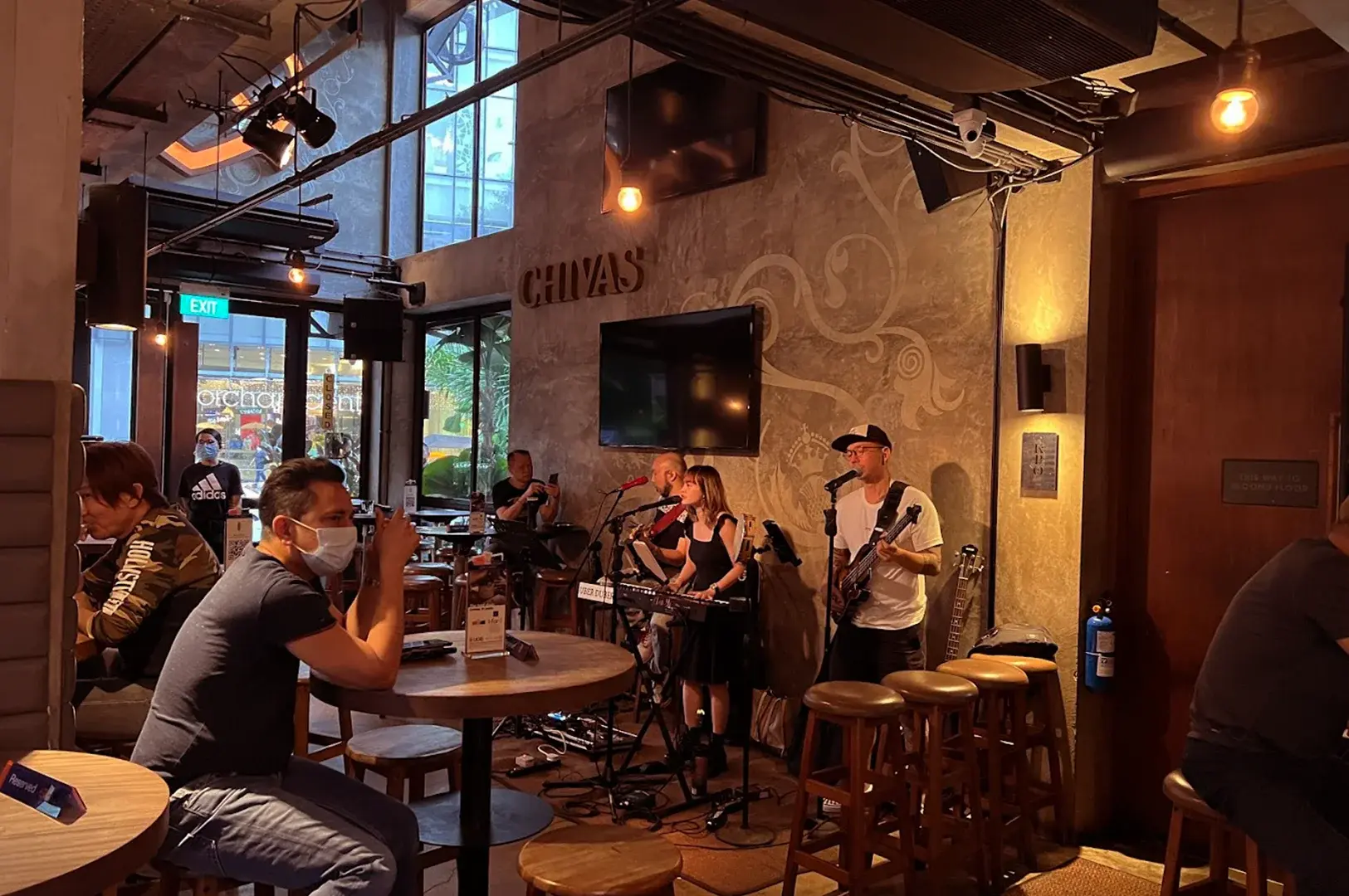Live music performance inside the warm, ambient interior of KPO Café Bar, with patrons seated at wooden tables enjoying the entertainment.