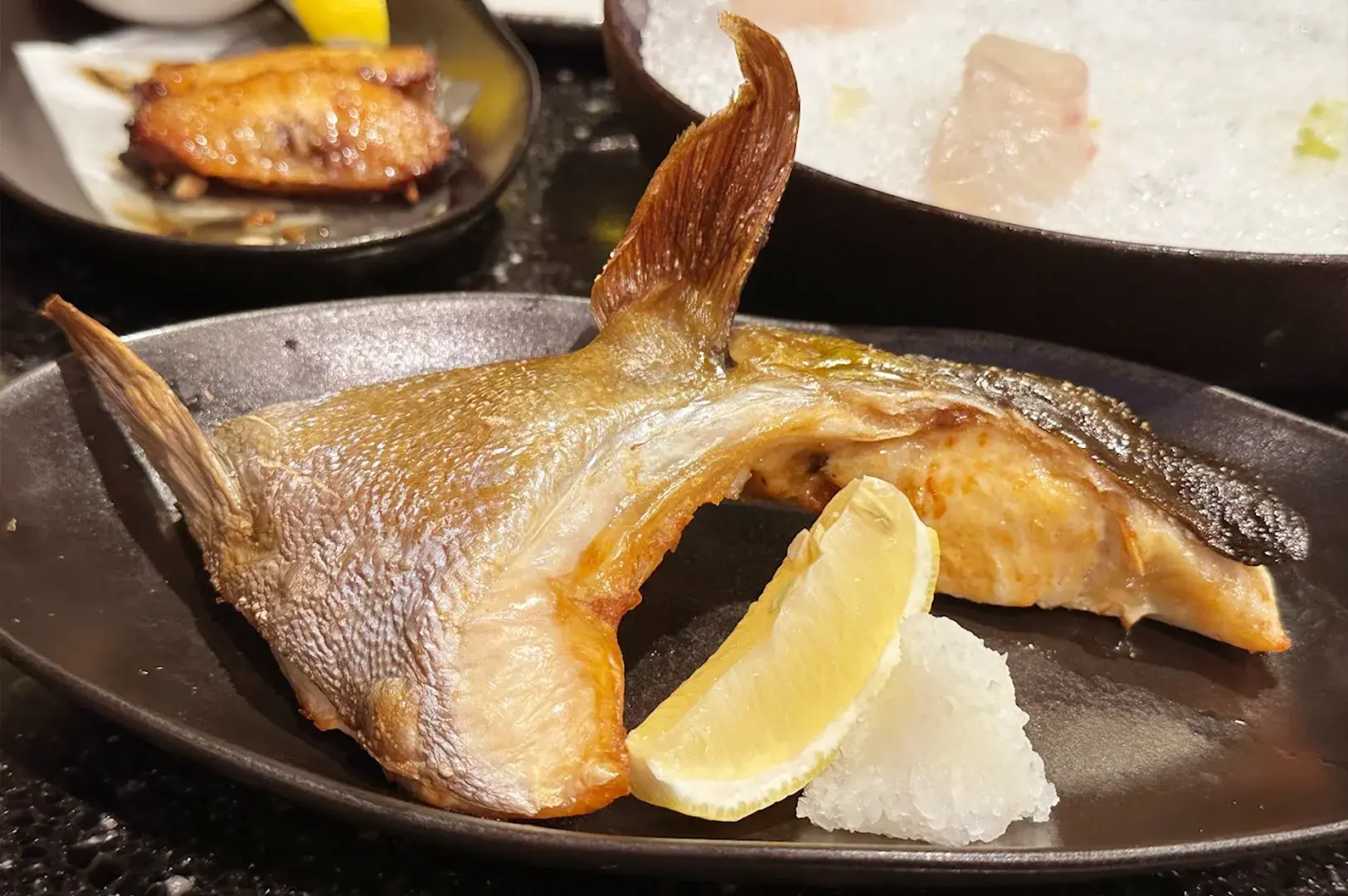 A perfectly grilled tuna kama (tuna collar) served with lemon and grated daikon radish at Kuro Maguro Sushi and Dining.