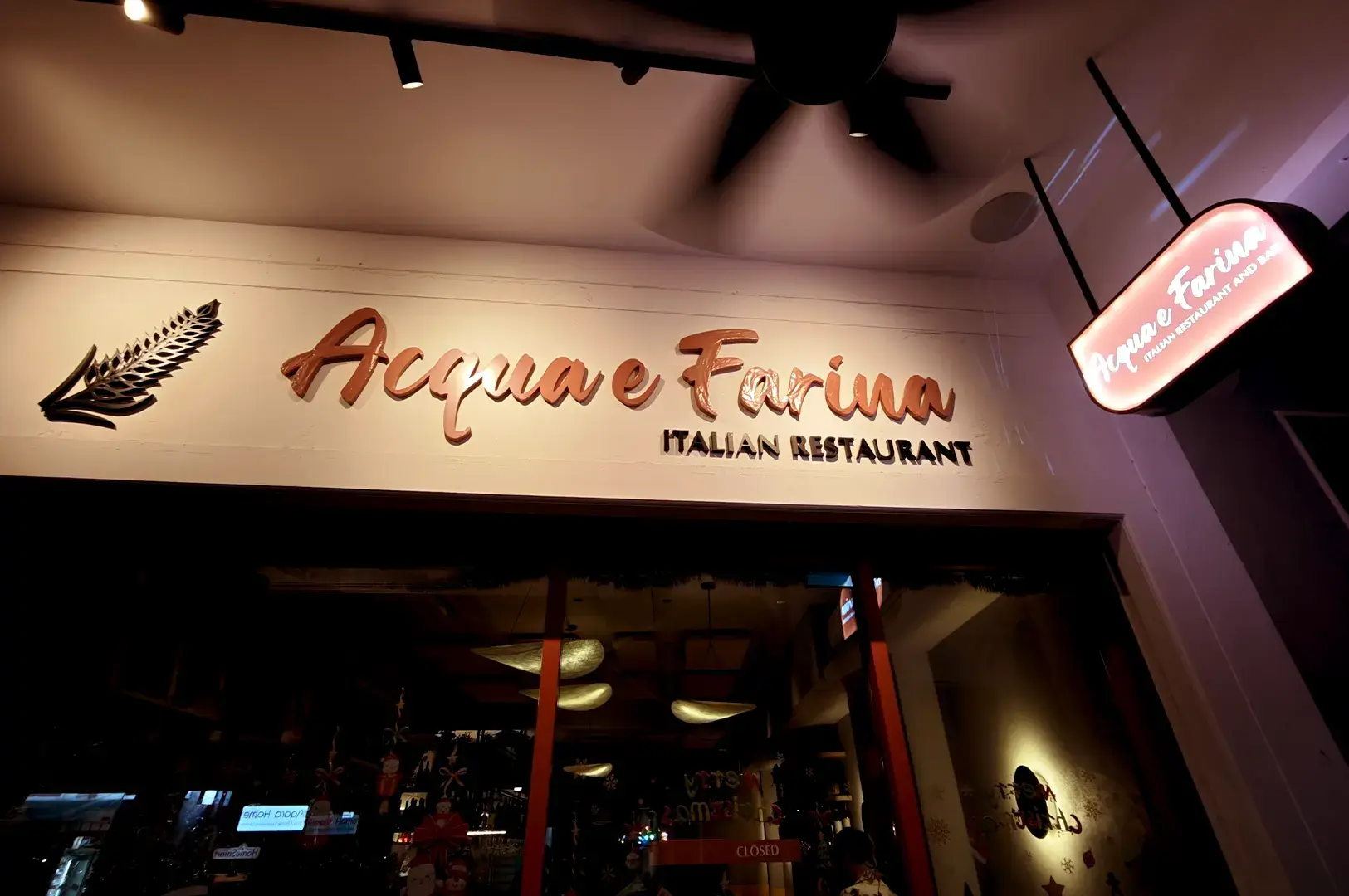A beautifully lit signage detail above the entrance of Acqua e Farina, highlighting the restaurant’s warm, welcoming atmosphere for Italian dining.