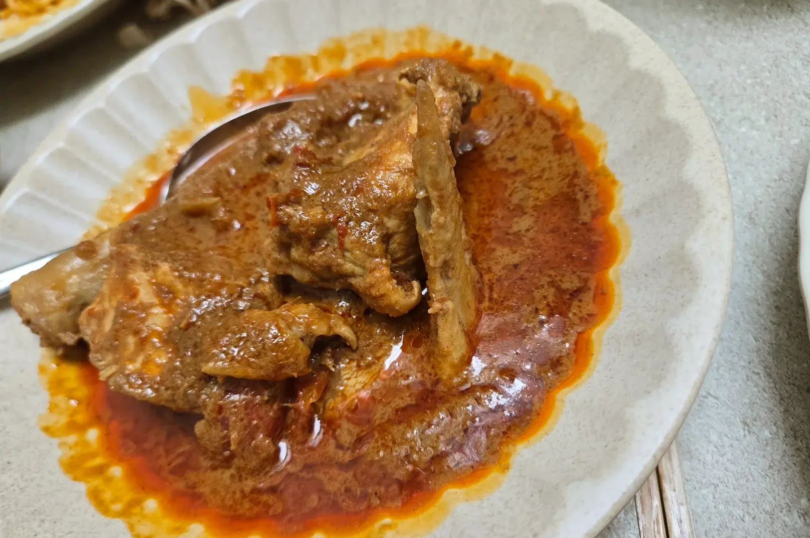 A hearty serving of traditional chicken curry in a bowl, showcasing the authentic, slow-cooked heritage recipes served at Rempapa.