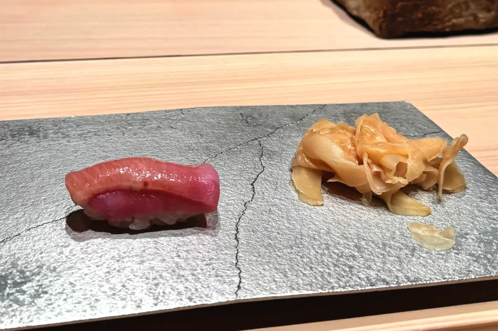 A single piece of premium nigiri sushi served on an elegant plate, representing the high-end sushi experience in Singapore.