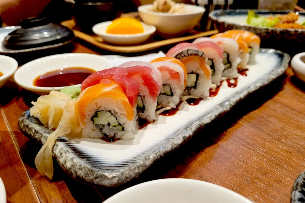 A close-up of a colorful sashimi sushi roll platter at Kuro Maguro, Tanjong Pagar, served on a stone slate with fresh wasabi and ginger, highlighting how fine dining fosters a sense of presence and stillness in every bite.