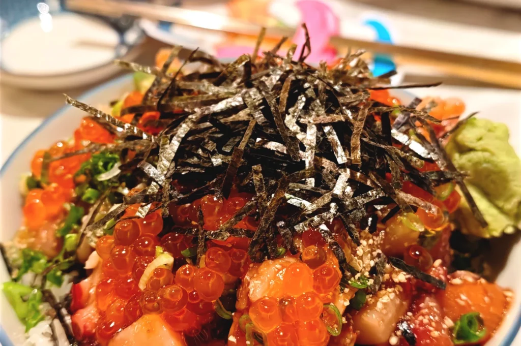 Close-up of the signature Umami Soy chirashi bowl at Omote, featuring fresh diced sashimi topped with generous portions of salmon roe and shredded nori seaweed.