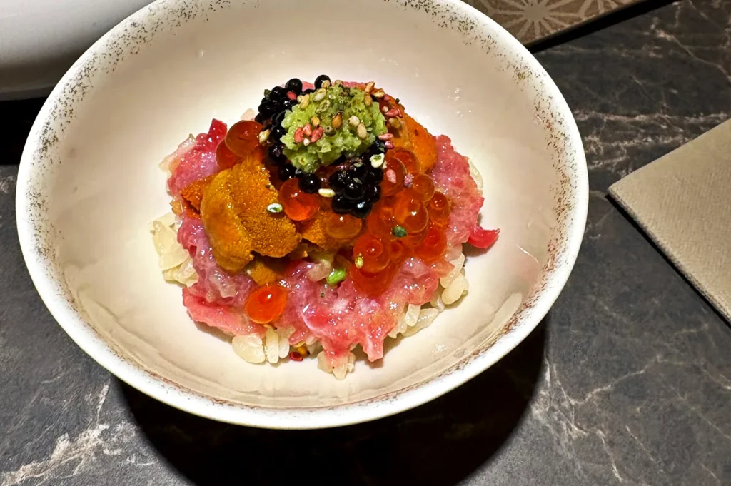 A close-up of the Snow crab ikura don from Sushi Jin, featuring a vibrant, gourmet arrangement of crab, salmon roe, and sea urchin.