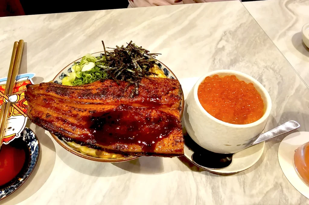 Premium grilled unagi eel chirashi bowl served with a side cup of fresh salmon roe at Omote, a premier Japanese dining destination in Singapore.