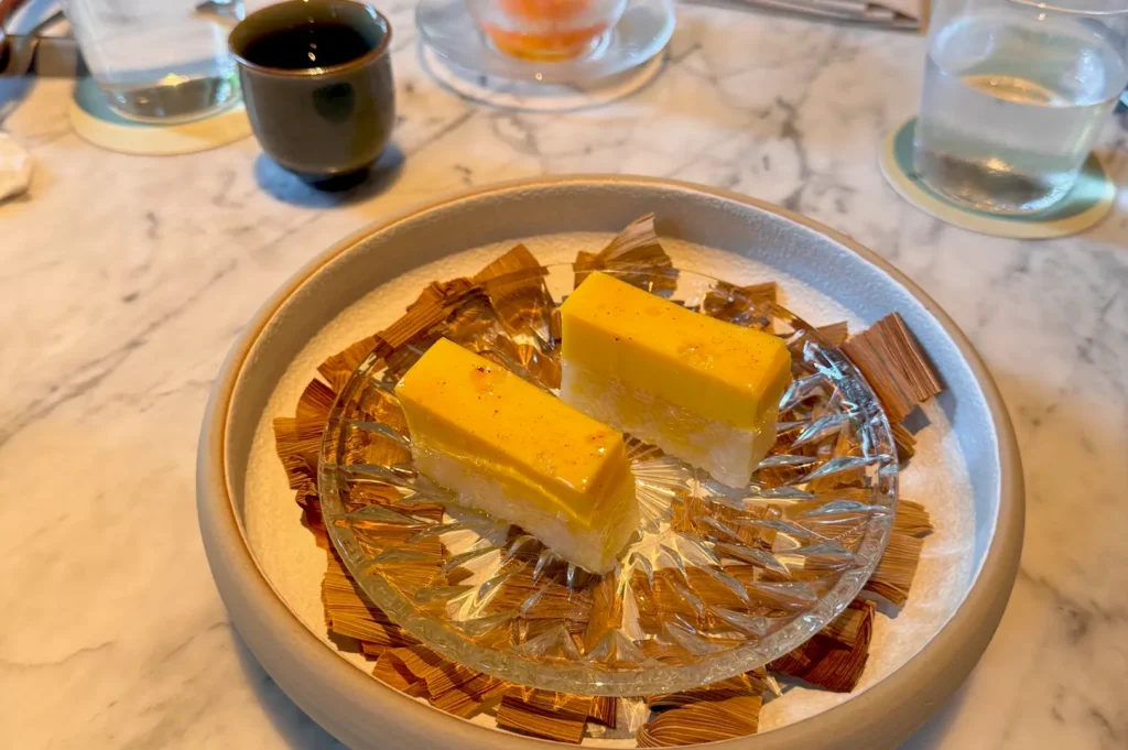 Elegant dessert of corn salat served on a decorative glass plate over dried husks, a signature of Belimbing’s modern dessert menu.