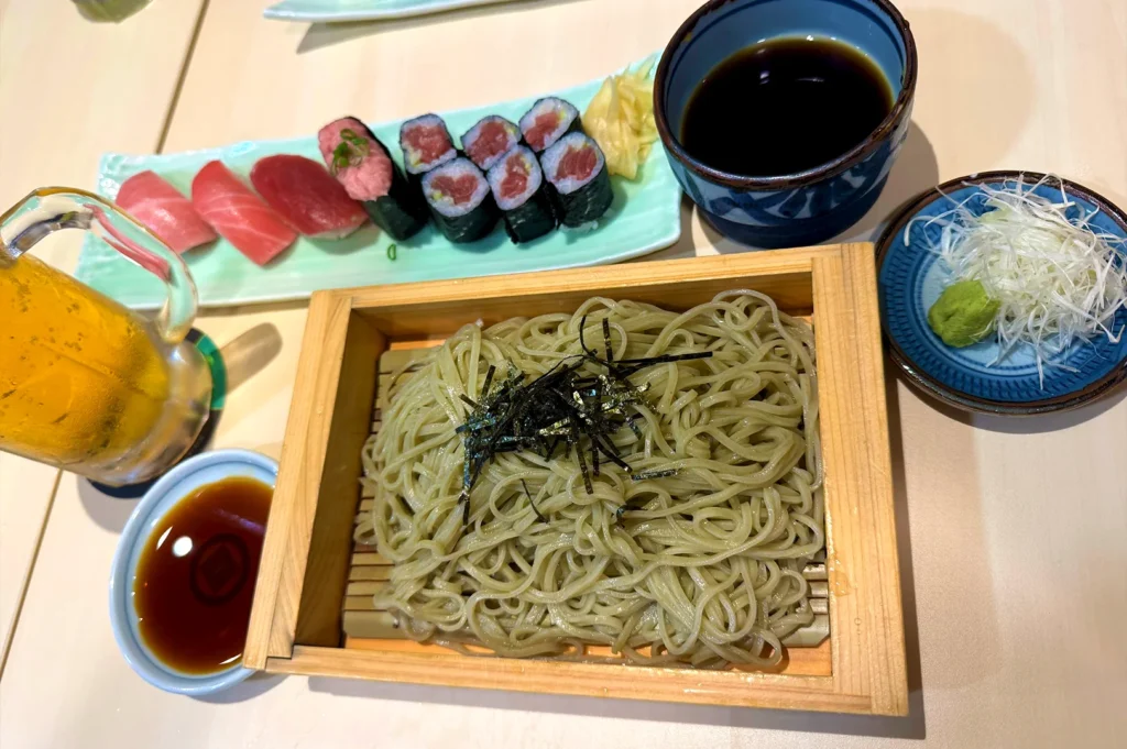 A traditional set meal featuring fresh nigiri, sushi rolls, and chilled soba noodles from Tomi Sushi, highlighting their commitment to authentic Japanese culinary standards.