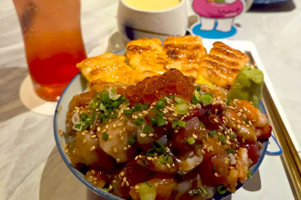 A fresh Tamago Mentai Chirashi bowl featuring seared egg and salmon roe, served with a refreshing iced drink at Omote Japanese restaurant.