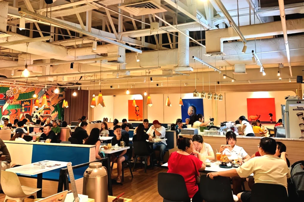 The vibrant, modern interior dining area of Omote, a bustling Japanese restaurant in Singapore decorated with colorful and playful wall art.