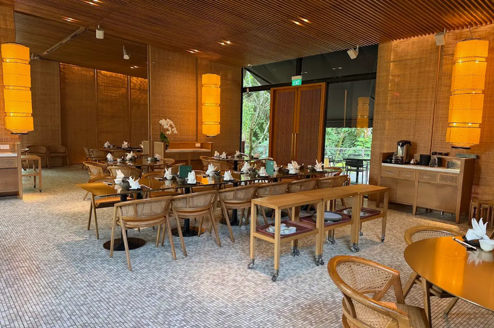 Elegant interior of Min Jiang at Dempsey restaurant, featuring warm lighting, rattan furniture, and a sophisticated atmosphere for fine Cantonese and Sichuan dining in Singapore.