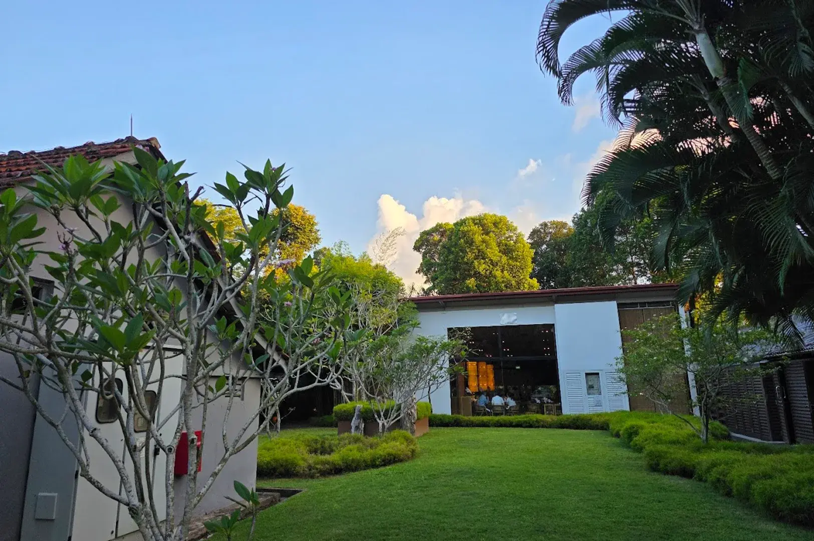 Scenic view of the lush, green surroundings and peaceful lawn outside Min Jiang at Dempsey, illustrating the restaurant's serene and idyllic location at Dempsey Hill.