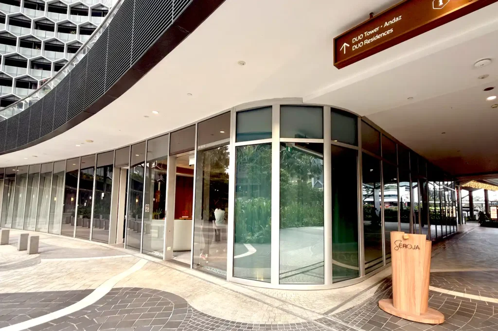 The exterior storefront of Seroja, a two Michelin-star restaurant celebrating the Malay Archipelago in Singapore, featuring a modern glass facade and wooden signage.